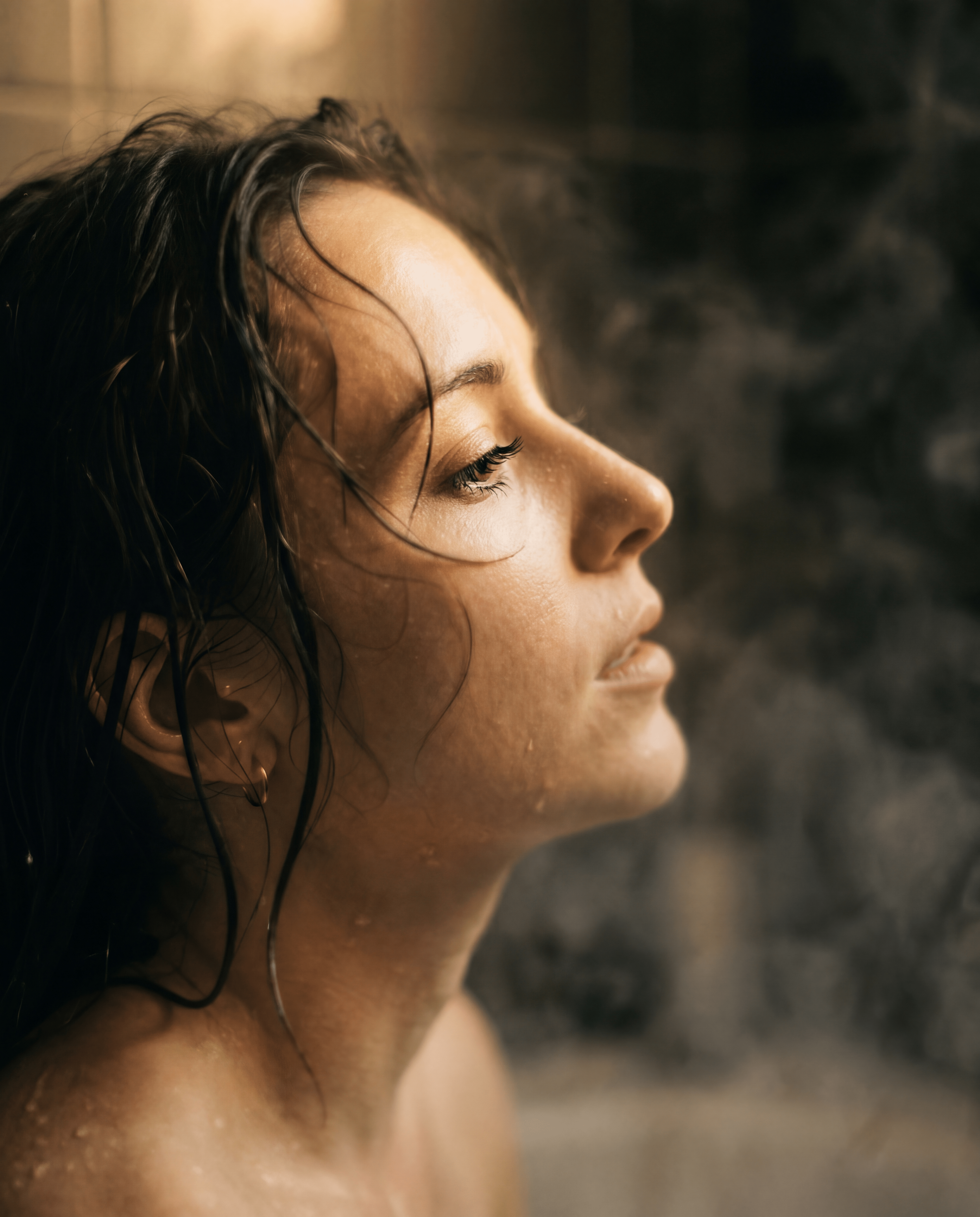 Woman's profile with closed eyes in warm steam — the 10pm exhale
