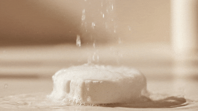 Ritual Cube dissolving under running water — fizzing and releasing essential oil steam